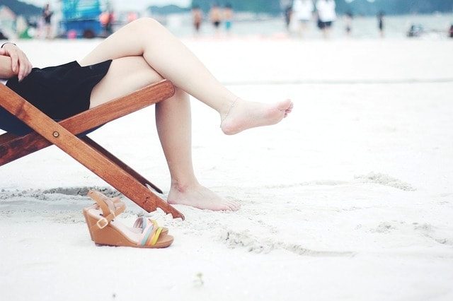 浜辺で椅子に座っている素足の女性。