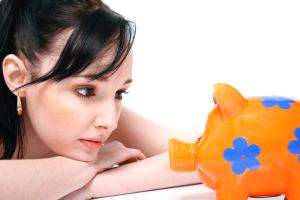 豚の貯金箱を眺める美少女。