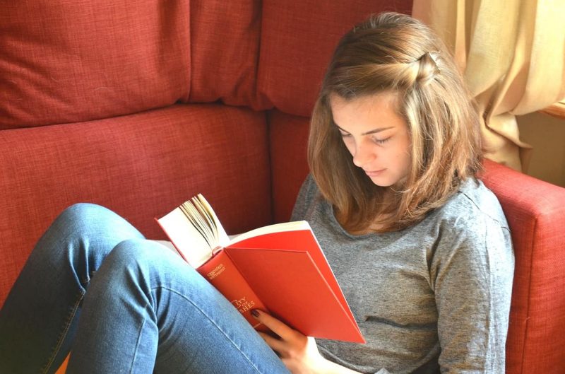 ソファーに座って本を読む美少女。