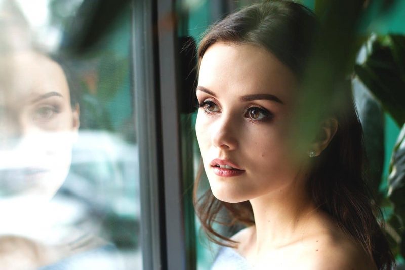 窓越しに外を見る美女。