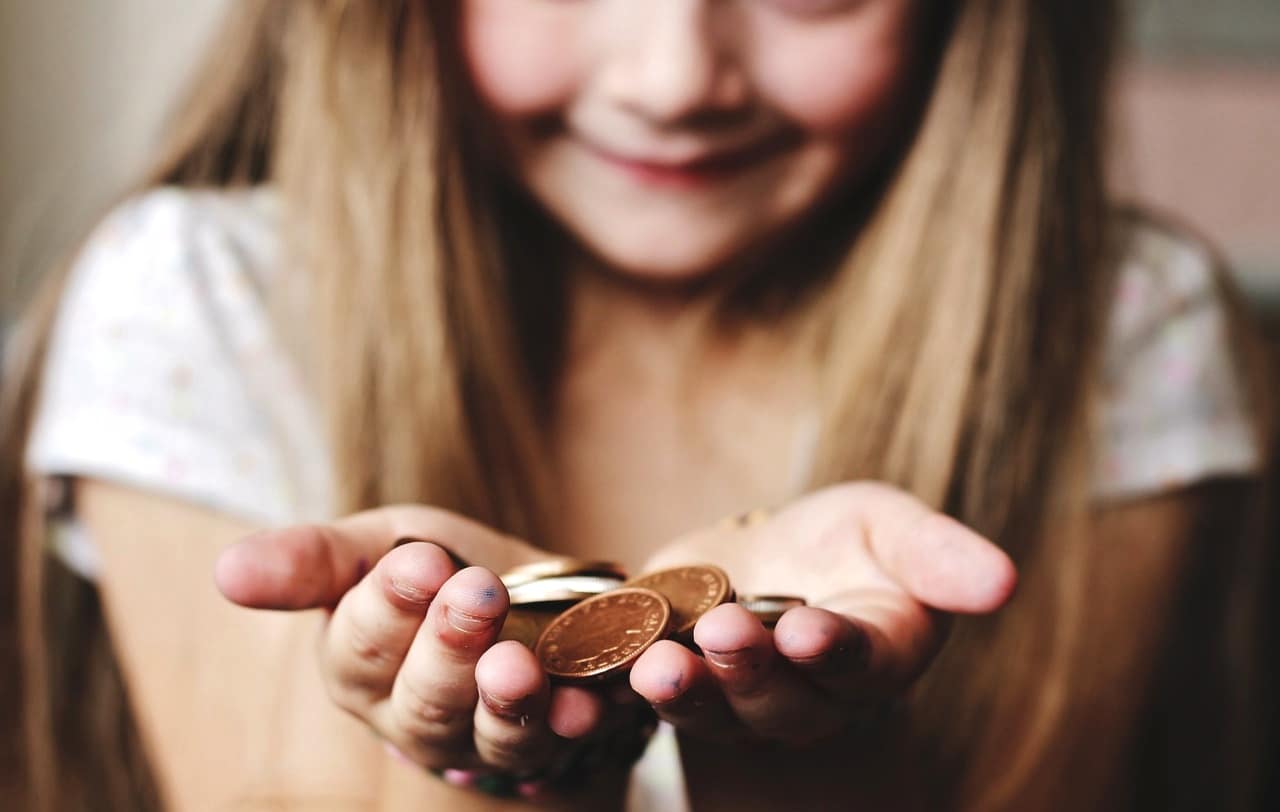 硬貨を手の上にのせて微笑む美少女。