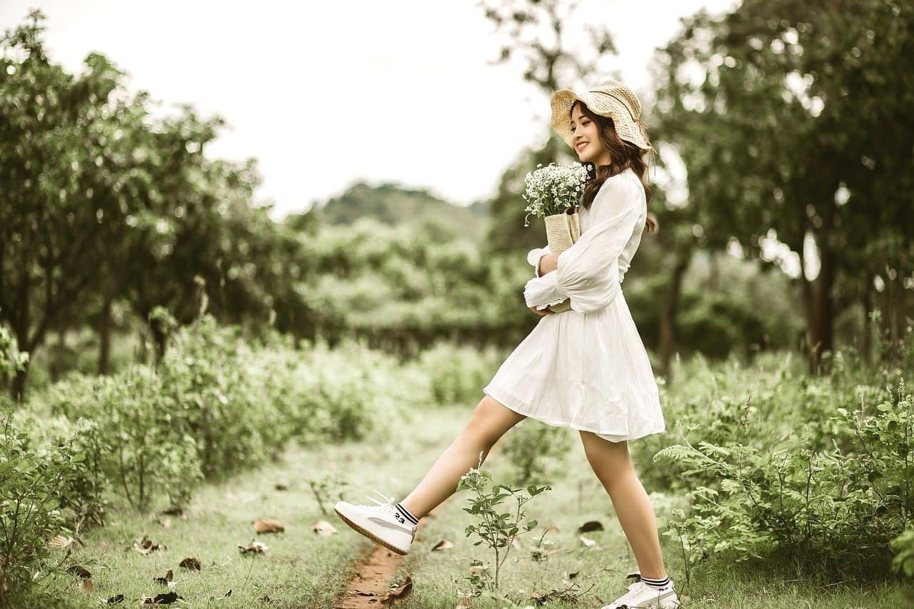 自然の中を花を持って歩く美少女。