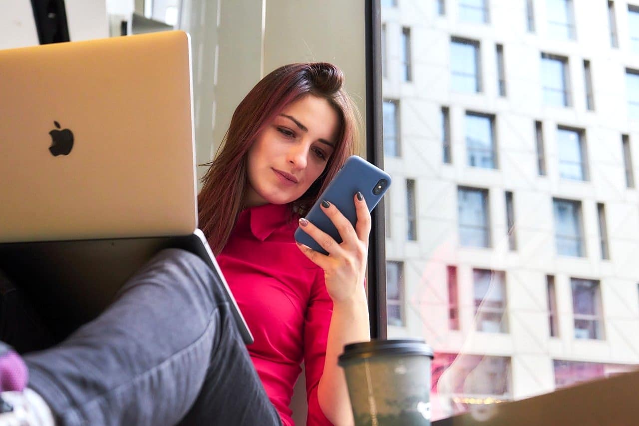 若い女性がパソコンとスマホで仕事を探している。